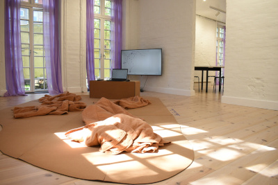 The exhibition installation, a comfortable floor with cushions and blankets, and a computer