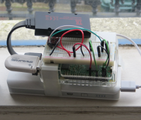 A Raspberry Pi circuit strapped to a USB battery, with a breadboard and wires above it.